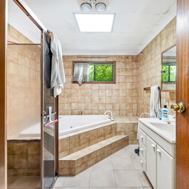 Bathroom before — brown wall tiles and an old bath surround