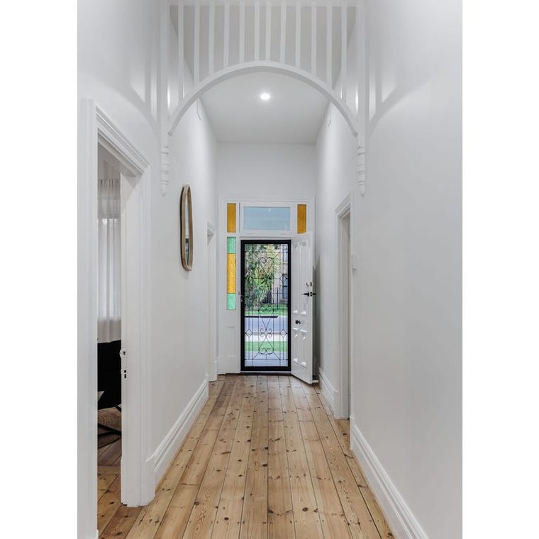 The same hallway after — white walls, restored arch, polished timber floor