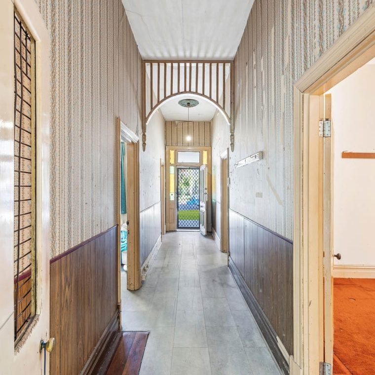 Hallway before — dark timber dado, patterned walls, worn floor