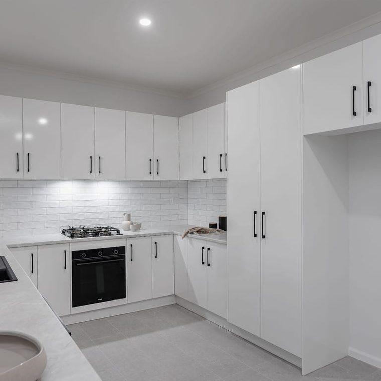 Kitchen after — white cabinetry, stone bench and black tapware