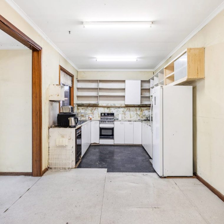 Kitchen before — dated cabinetry under fluorescent light
